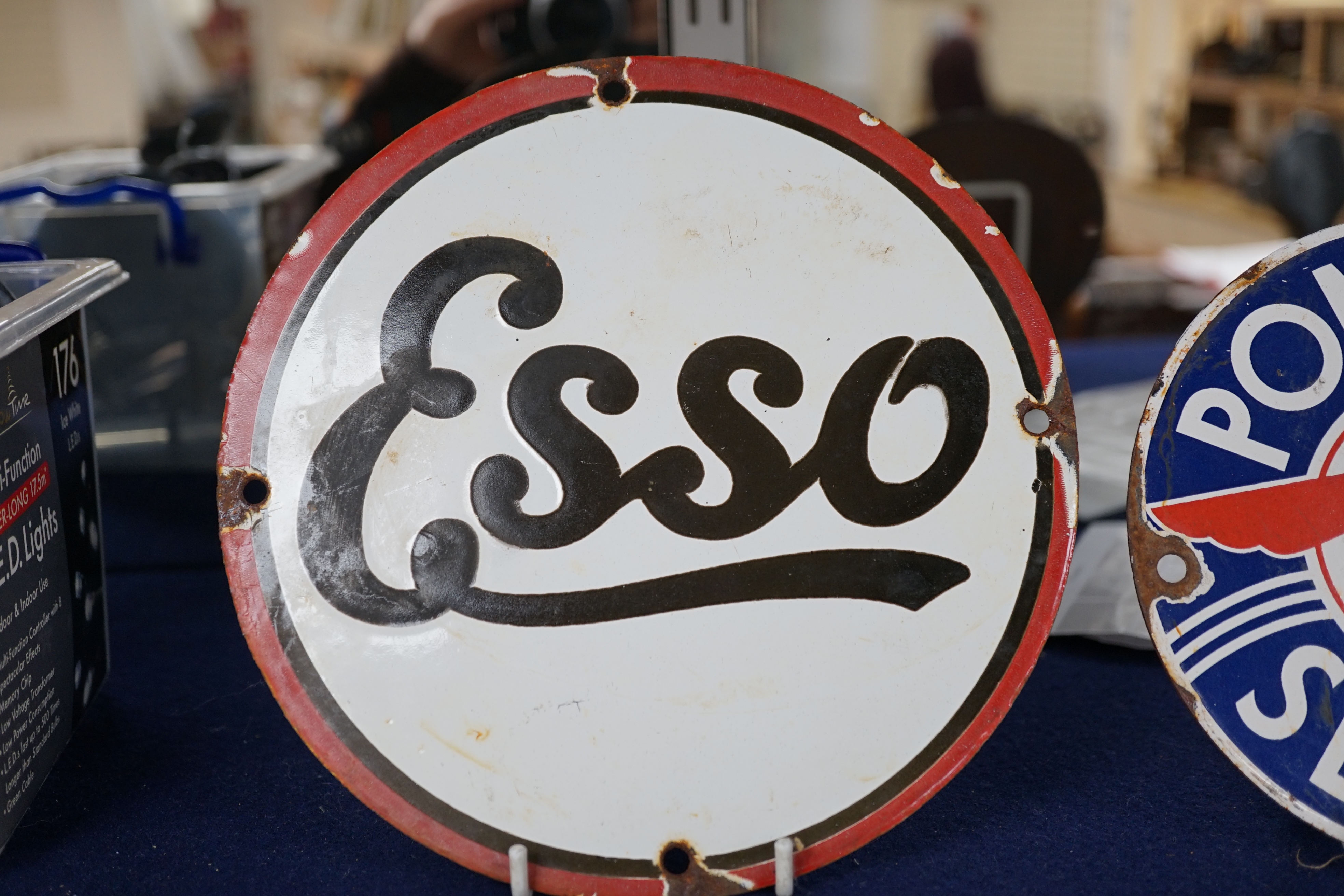 Automobilia interest; an early 20th century Esso enamel sign, diameter 20cm, and a Pontiac Service enamel sign, diameter 15cm. Condition fair to good, some chipping around the screw holes and surface rust to exposed meta